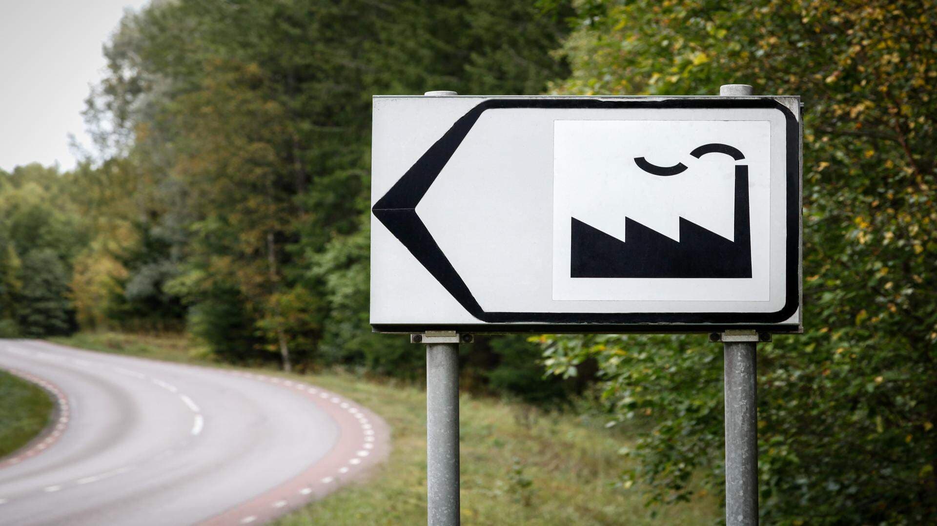 Skylt mot industriområde på enslig skogsväg