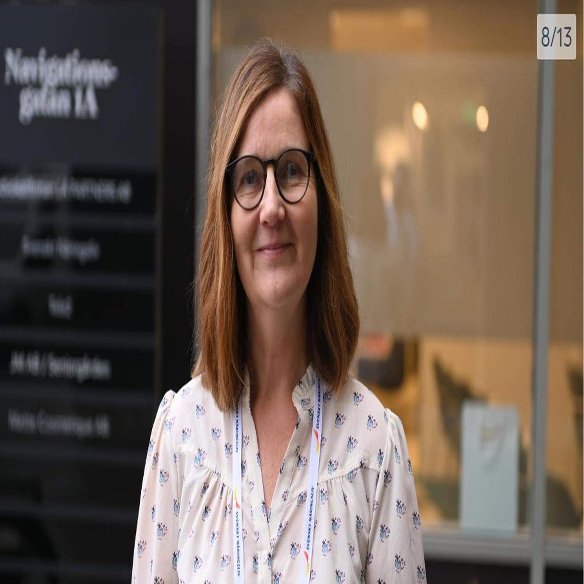 Bilden föreställer en glad kvinna med glasögon