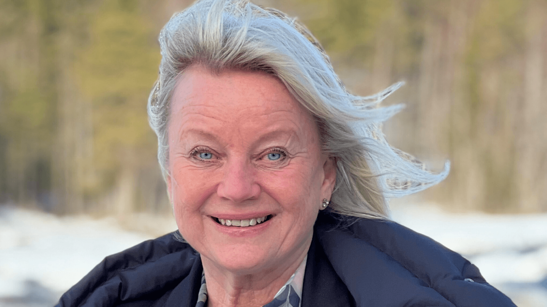 Caroline Nyström står utomhus med en blå kappa