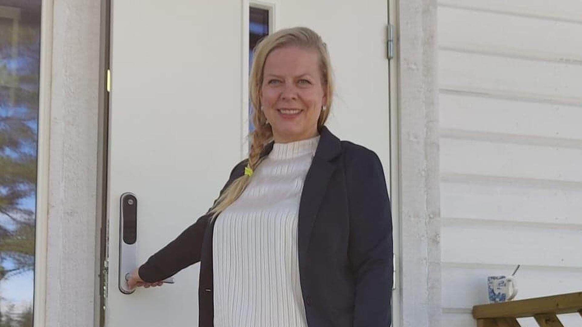 Elisabeth Landby står på en trappa vid en öppen dörr