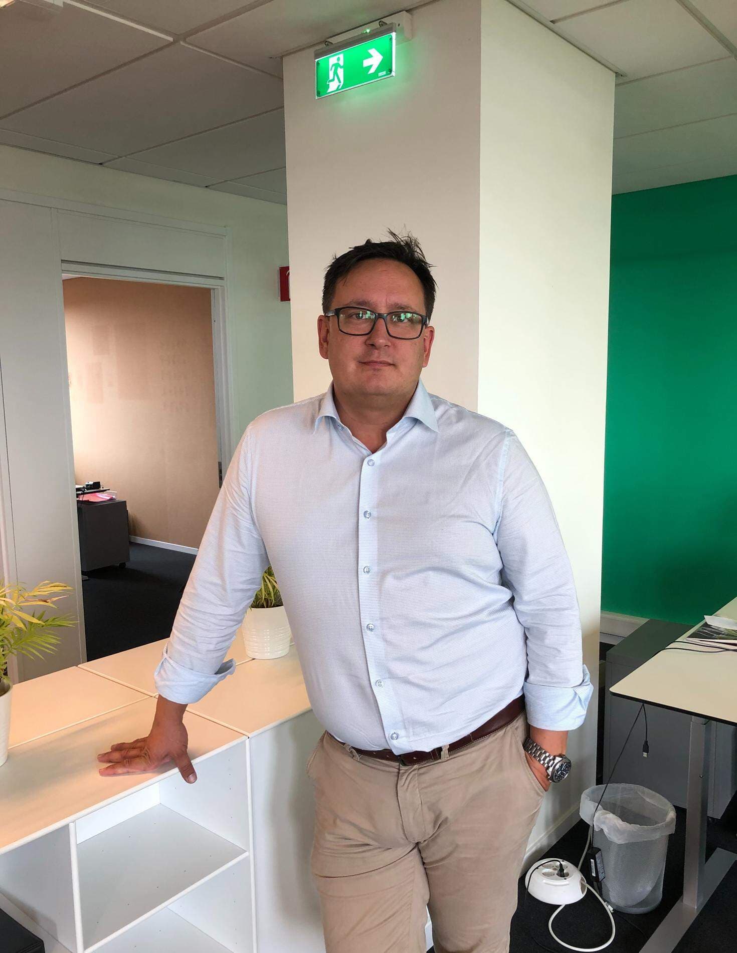 Anders Fall, vd Danica Foods, har en vit skjorta och står med armen lutande mot ett bord.