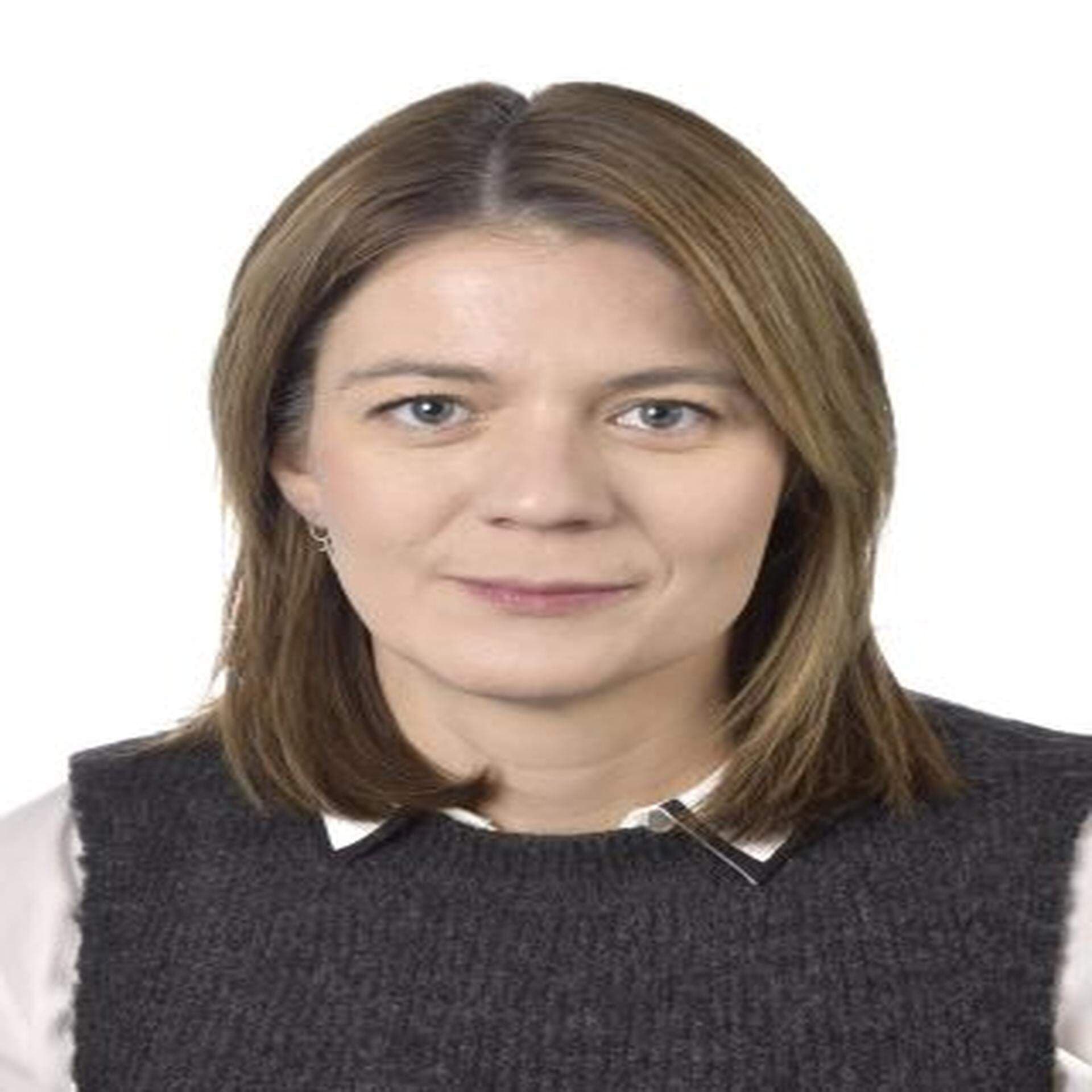 Johanna Haraldsson i vit skjorta och grå slipover med vid bakgrund