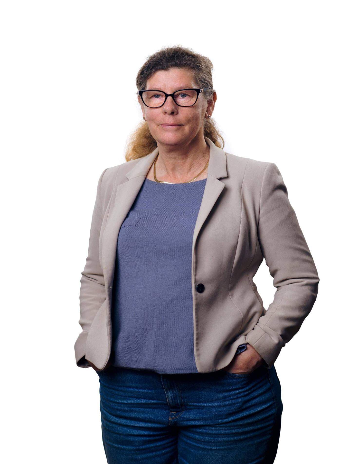 Edit Karlsson Håål i blå topp och grå kavaj. Bakgrunden är vit.