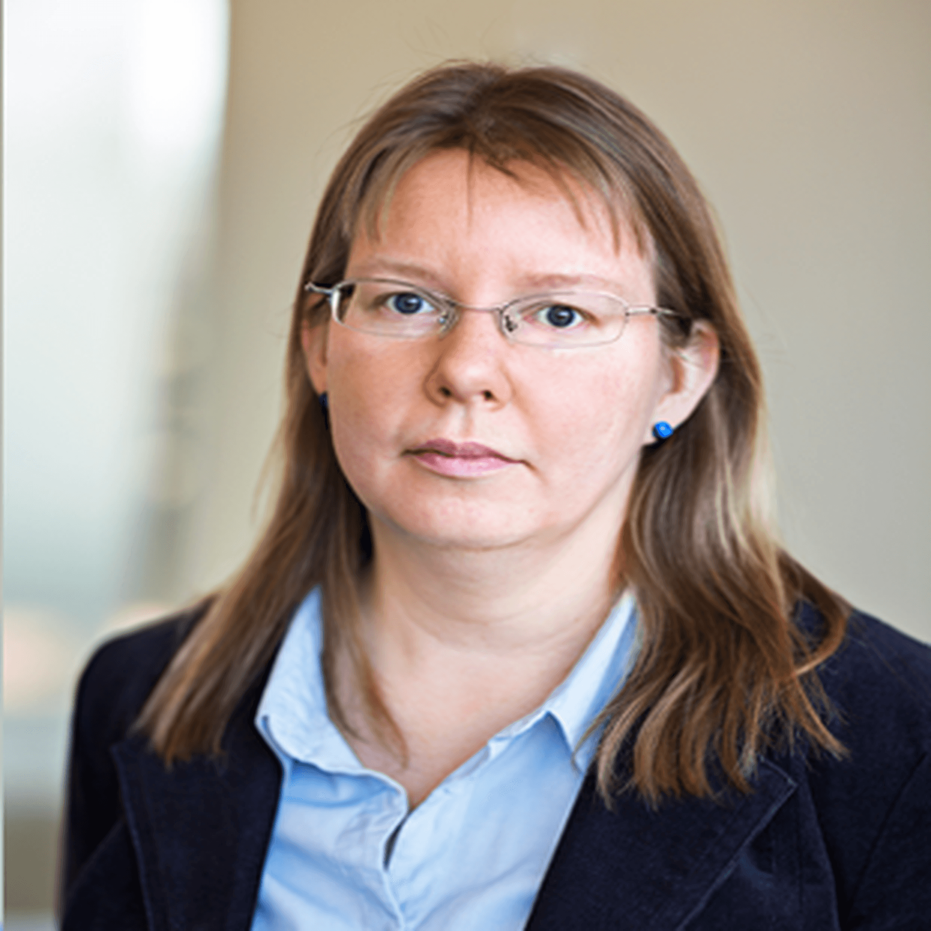 Johanna Skinnari i ljusblå skjorta och kavaj. Bakgrunden är grå-beige.