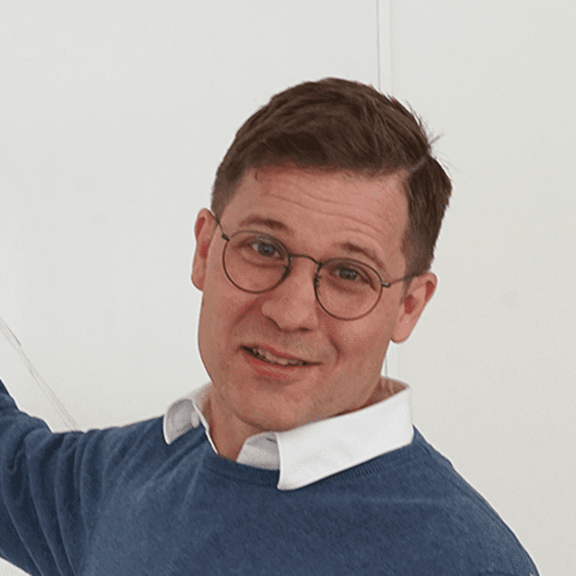 Johan Prytz pekandes på en whiteboard. Han har en mörkblå stickad tröja och svarta byxor samt runda glasögon