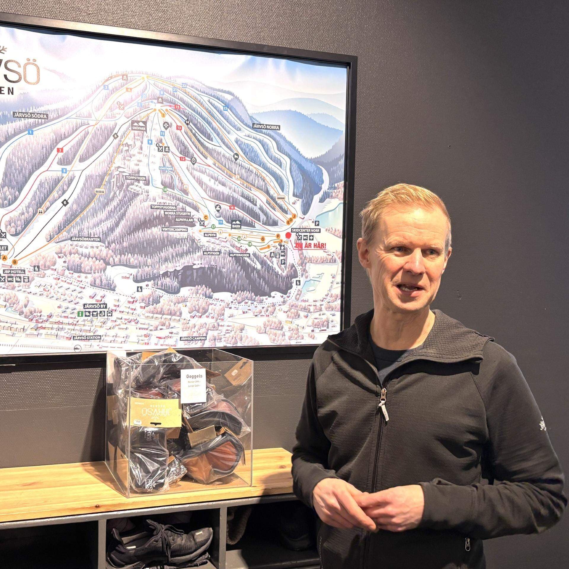 Peter Augustsson, delägare och vd för Järvsöbacken står framför en bild av Järvsöbacken.