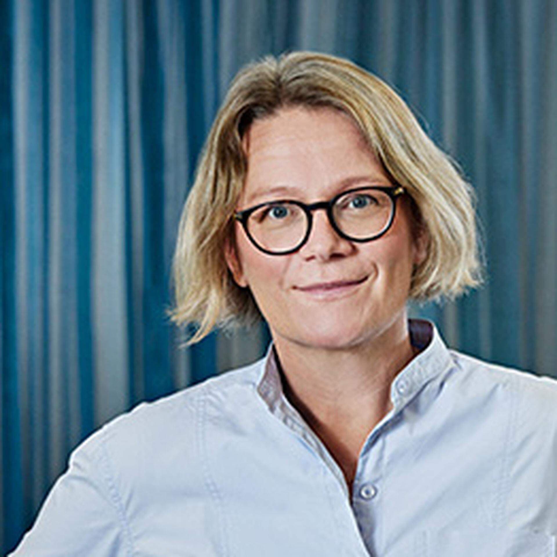 Sofia Hylander i blond page, runda bruna glasögon och ljusblå skjorta