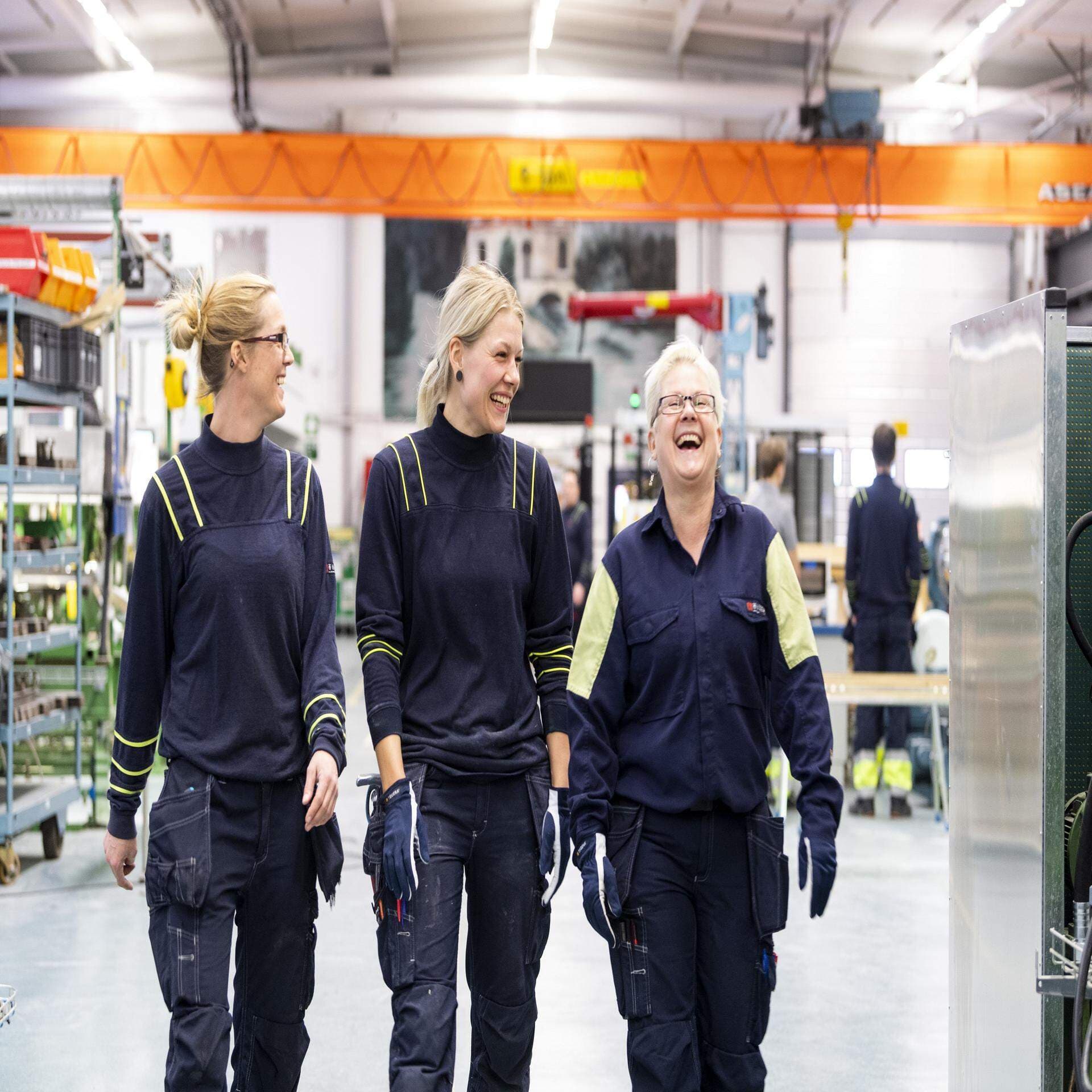 Tre yrkesarbetare går igenom produktionen och skrattar