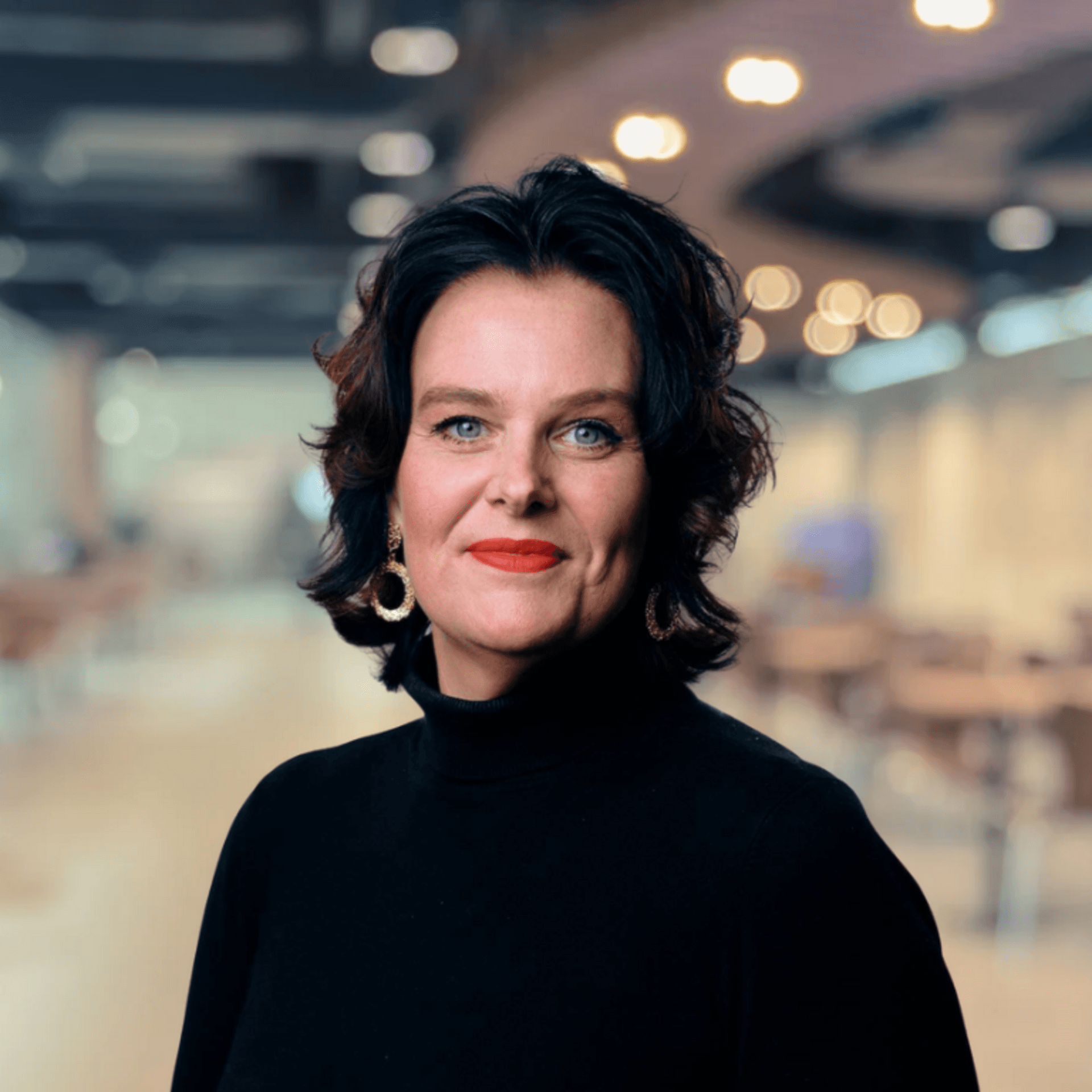 Ulrica Bennesved i förgrunden, ett suddigt rum med belysning i taket i bakgrunden.