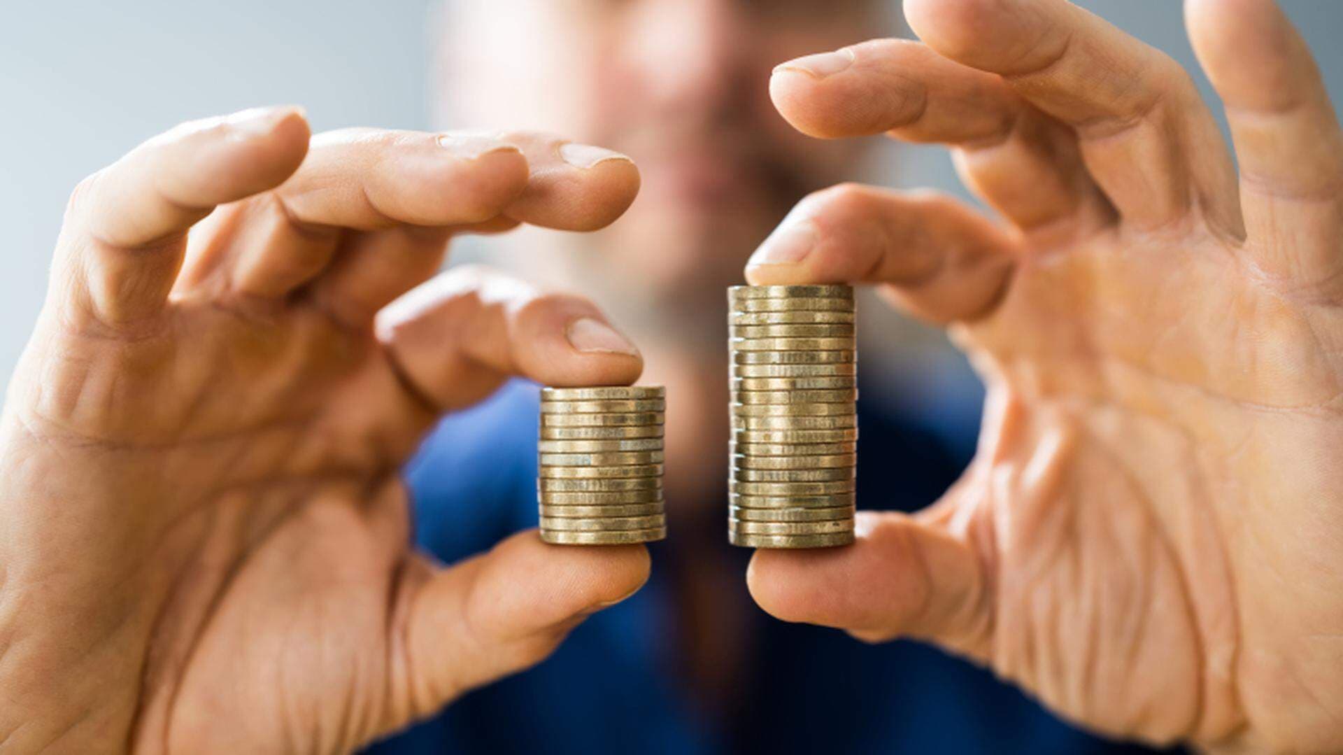 Två händer som håller fram två mynthögar