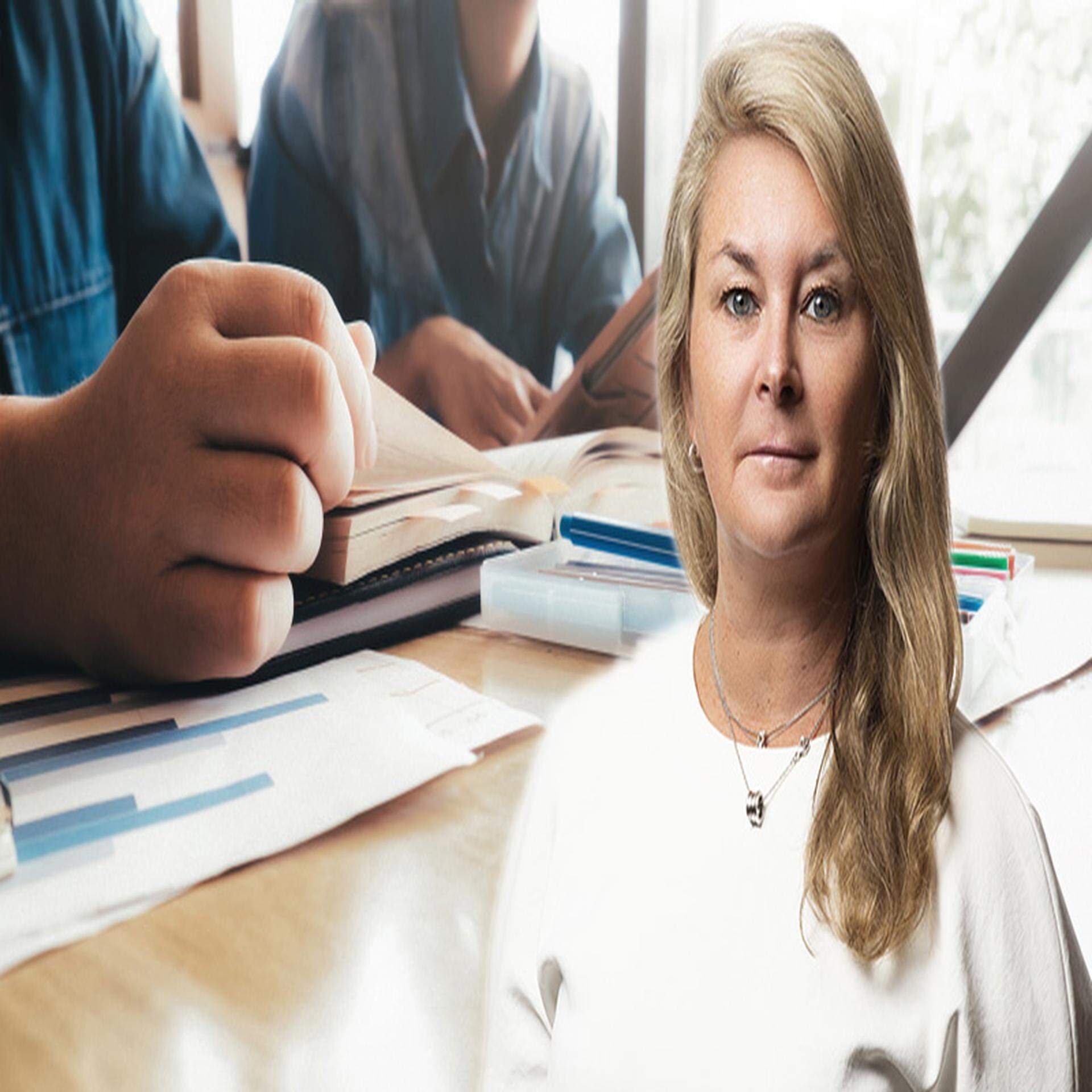 Ulrika Wallén och i bakgrunden två personer vid ett skrivbord med en laptop