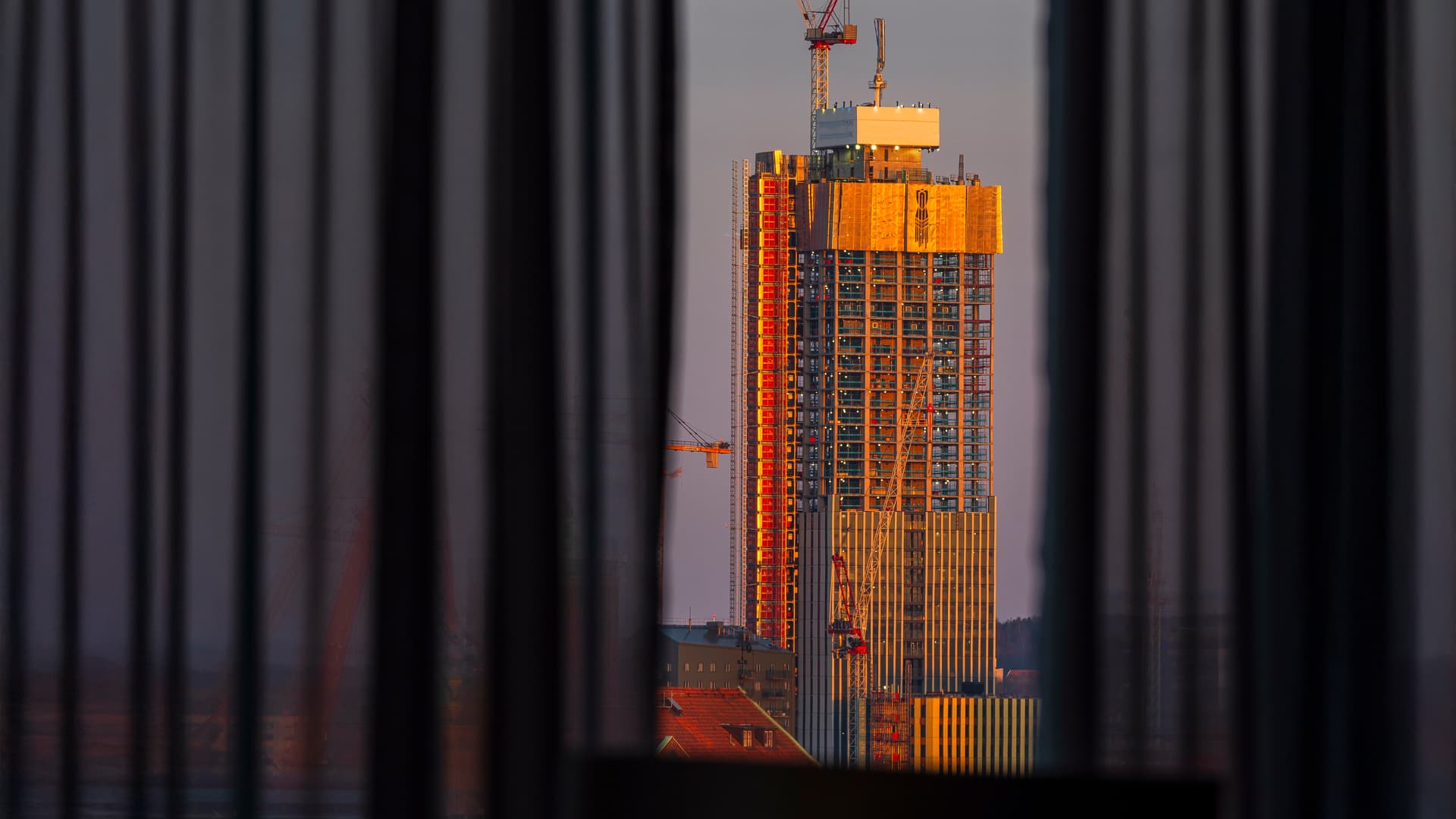 Husbygge i skymningsljus skiktad bakom en gardin