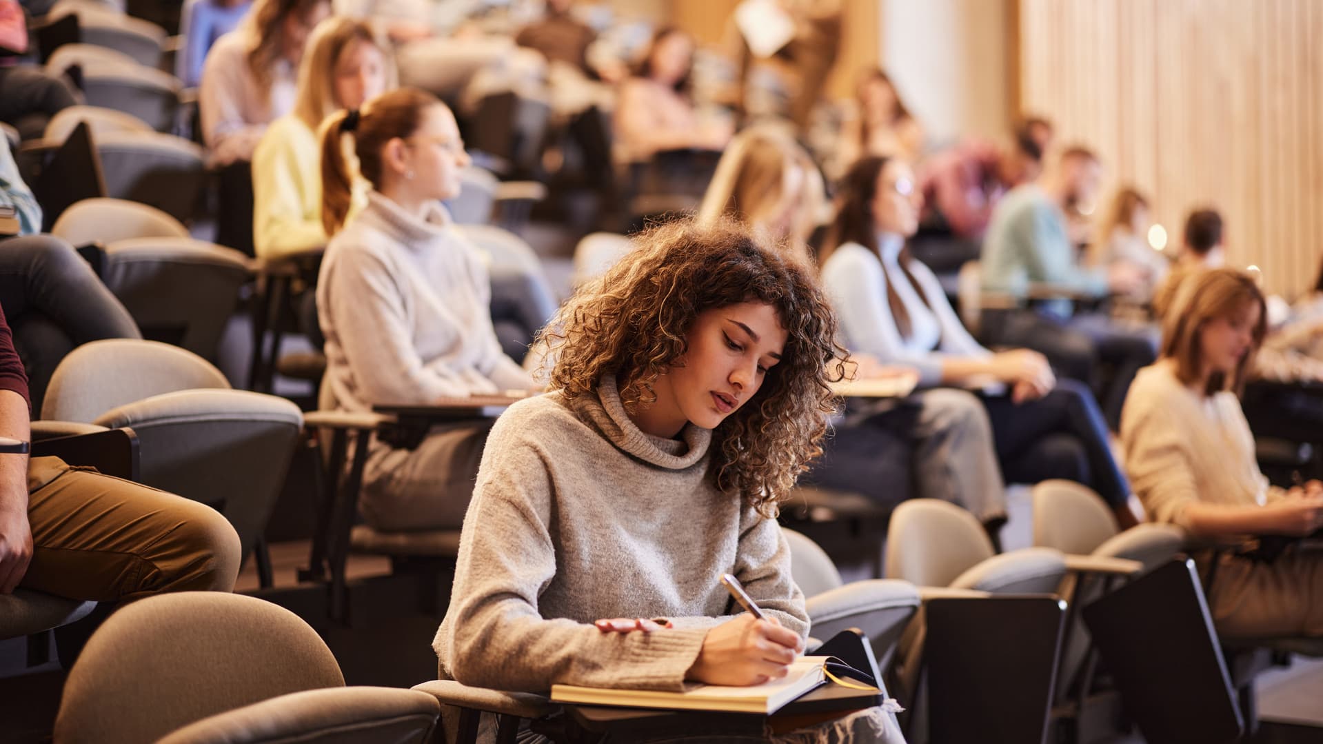 Kvinnlig student i en halvfull föreläsningssal